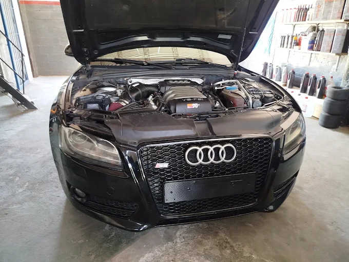Audi negro con el capó abierto en Pagano Racing para revisión del motor